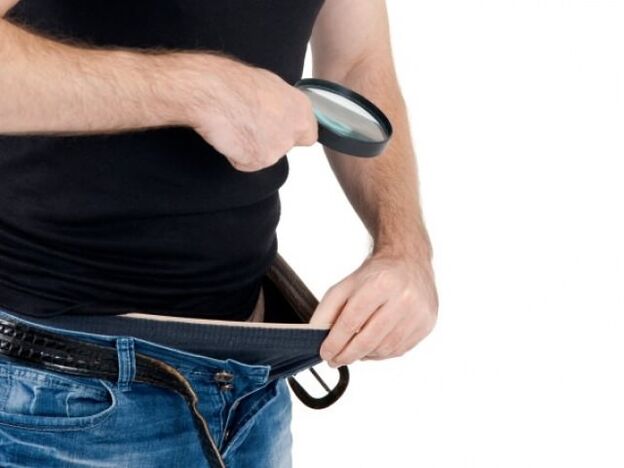 一个男人低头看自己的裤子，想要增大他的阴茎